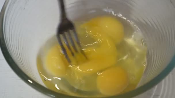 Девушка хлещет вилку куриными яйцами в стеклянной миске на кухне, чтобы сделать омлет. Крупный план. Вид с вершины. 4К. 25 кадров в секунду — стоковое видео