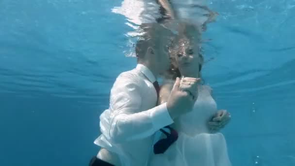 화창한 날에 푸른 배경에 수영장에서 키스하고 수중 포옹 흰색 드레스에 매력적인 신부와 신랑. 초상화. 닫아. 4k. 29.97fps — 비디오