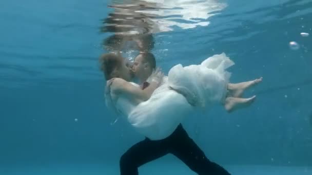 Svatba pod vodou. Muž a dívka na svatebních šatech se obejmi, ponoříme se pod vodu a políbí. Portrét. Zavři to. 4k. 29,97 fps — Stock video