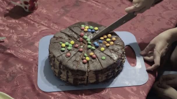 Una mujer corta un pastel de chocolate en pedazos con un cuchillo grande durante unas vacaciones familiares en casa. De cerca. La vista desde arriba. 4K — Vídeo de stock