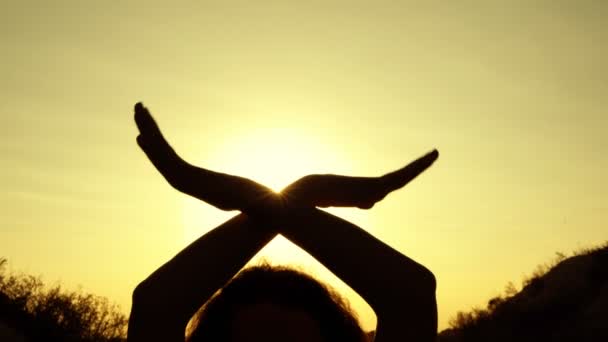Силуэт женских рук на закате солнца в форме крыльев. Девушка держит их скрещенными над головой и машет, как птица, против ярких лучей заходящего солнца. Концепция. Закрывай. 4K . — стоковое видео