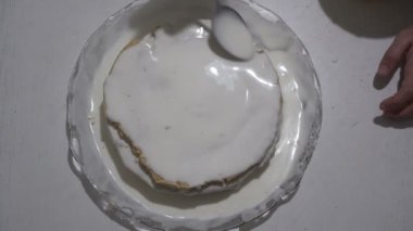 Beyaz krema ile sünger kek sulama adam ve yüzeye smear. Tatlı tatlısı hazırlığı. Yukarıdan manzara. 4k.