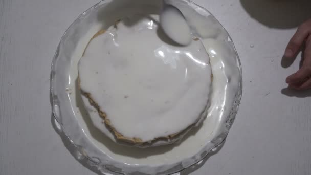 Чоловік поливає губний торт білим кремом і мазає його на поверхні. Приготування солодкого десерту. Вид зверху. 4-кілометровий . — стокове відео