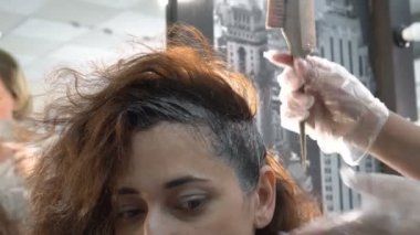 Yakın çekim, kuaför güzellik salonunda saç boyama işlemi sırasında Doğu uyruklu bir kızın saç boya uygular. 4k