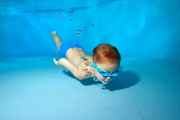 El chico de los deportes nada bajo el agua, se sumerge en el fondo de la piscina. Soplando burbujas bajo el agua. Retrato. Foto bajo el agua. Orientación horizontal — Foto de Stock