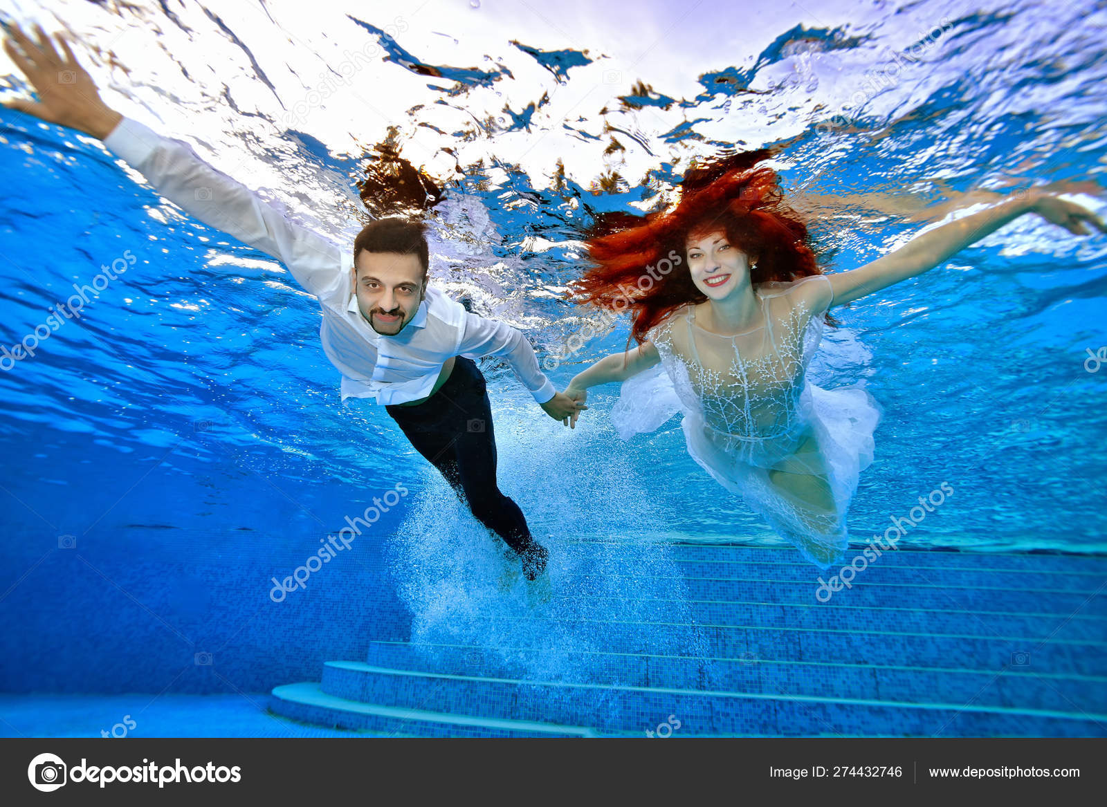 Beautiful bride and groom in wedding dresses swim underwater in