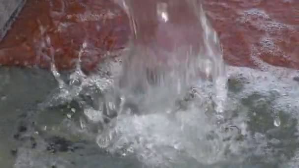 Des gouttes d'eau se rapprochent qui tombent sur la pierre de granit dans la fontaine de la ville. Mouvement lent . — Video