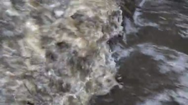 Çamurlu bir dere, kayalar karşı çökmesi su köpürme. Üstteki görünüm. Kapat şunu. 4k.