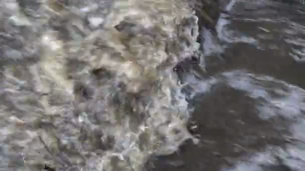 Een stroom van modderig, borrelend water dat tegen de rotsen crasht. Het uitzicht vanaf de top. Close-up. 4k. — Stockvideo