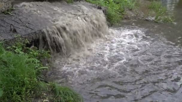 Água lamacenta após a chuva cai das lajes de concreto e flui para o rio. Pequena cascata. Fecha. 4K . — Vídeo de Stock