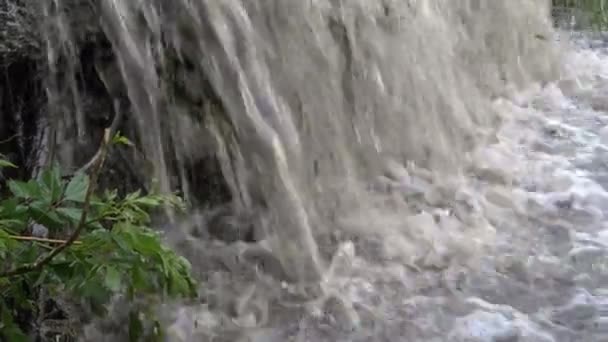 Close-up van de stroom van modderig borrelende water stroomt in de rivier. Kleine waterval. Close-up. 4k. — Stockvideo