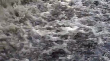 Son derece yakın-up nehir içine acele çamurlu kabarcıklanma su akışı. Küçük bir şelale. Kapat şunu. 4k.