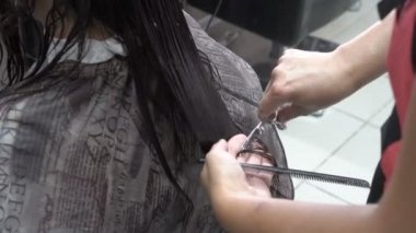 Bir güzellik salonunda profesyonel bir Kuaför tarafından uzun saç yakın çekim saç kesimi. Arka görünüm, üst görünüm. 4k.