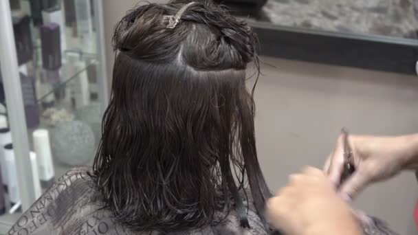 Das Mädchen im Friseursalon schneidet der Schere dunkle Haare. es entspricht der Länge jedes Strängs. Nahaufnahme. 4k. — Stockvideo
