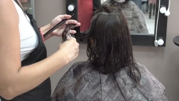 Las manos de un maestro barbero de cerca. Corta el pelo oscuro de una chica en un salón de belleza con tijeras. 4K . — Vídeos de Stock