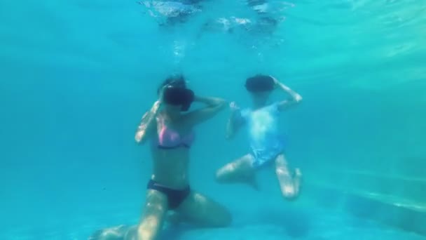 Moeder en kleine dochter duiken samen onder het water in Virtual Reality-brillen. Ze spelen virtuele spelletjes onderwater in het zwembad en blazen bubbels. Slow Motion. Concept video. 4k. — Stockvideo