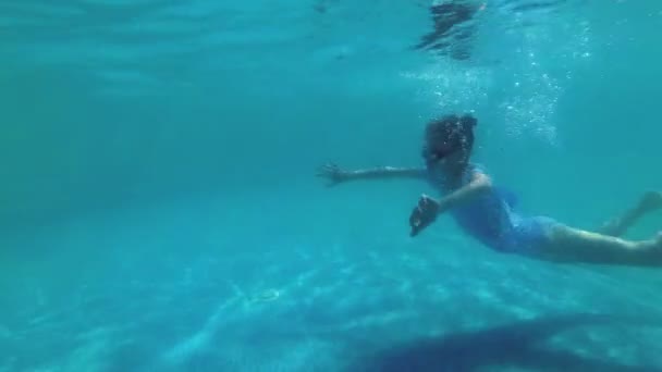 La niña va a nadar y se sumerge bajo el agua hasta el fondo de la piscina al aire libre en un día soleado brillante. Deporte. En cámara lenta. Primer plano. 4K . — Vídeo de stock