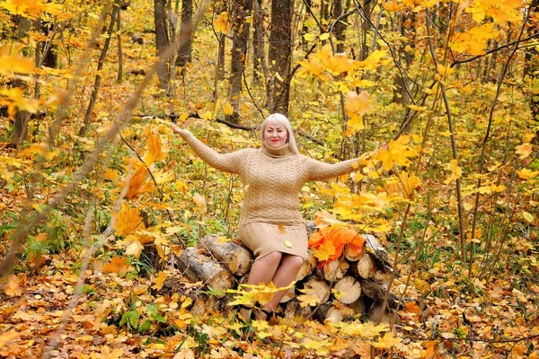 미소 짓는 금발이 단풍과 함께 숲에서 놀고, 그것을 내다보며. 프레임에 보이는 것이 기쁘고. 여성 플러스 크기 xxl. 가로 보기. 일반 계획 — 스톡 사진