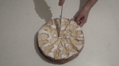 Yakın çekim, kadın elleri ev mutfakta beyaz bir masa üzerinde büyük bir mutfak bıçağı ile parçalarhalinde yuvarlak bir Elmalı pasta kesti. Üst te. 4k