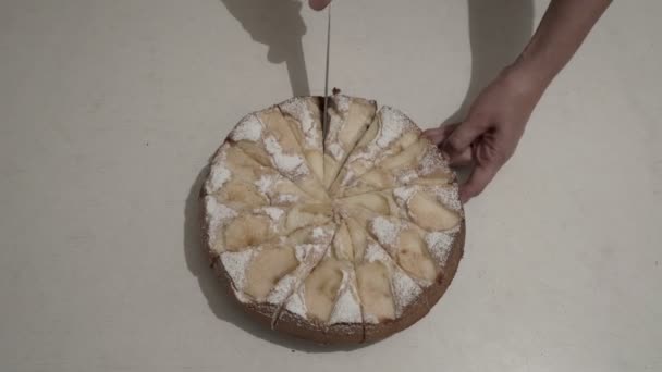 La mujer corta y toma un pedazo de tarta de manzana, que se encuentra en una mesa blanca en un plato en la cocina del hogar. Vista superior. 4K — Vídeo de stock