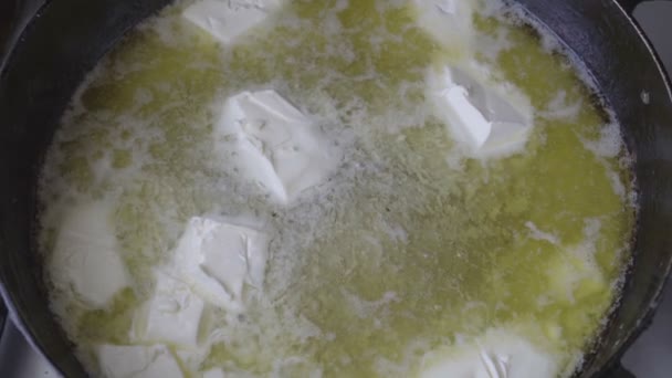 El cierre - los pedazos de la mantequilla que se derriten en la cacerola caliente. Cocinar. Vista superior. 4K — Vídeo de stock