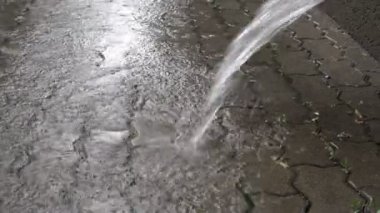 Yakın - şehirde yağmur sırasında kaldırım levhalar üzerine bir drenaj borusu dökülür su bir jet kadar. Zemin seviyesi görünümü. 4k