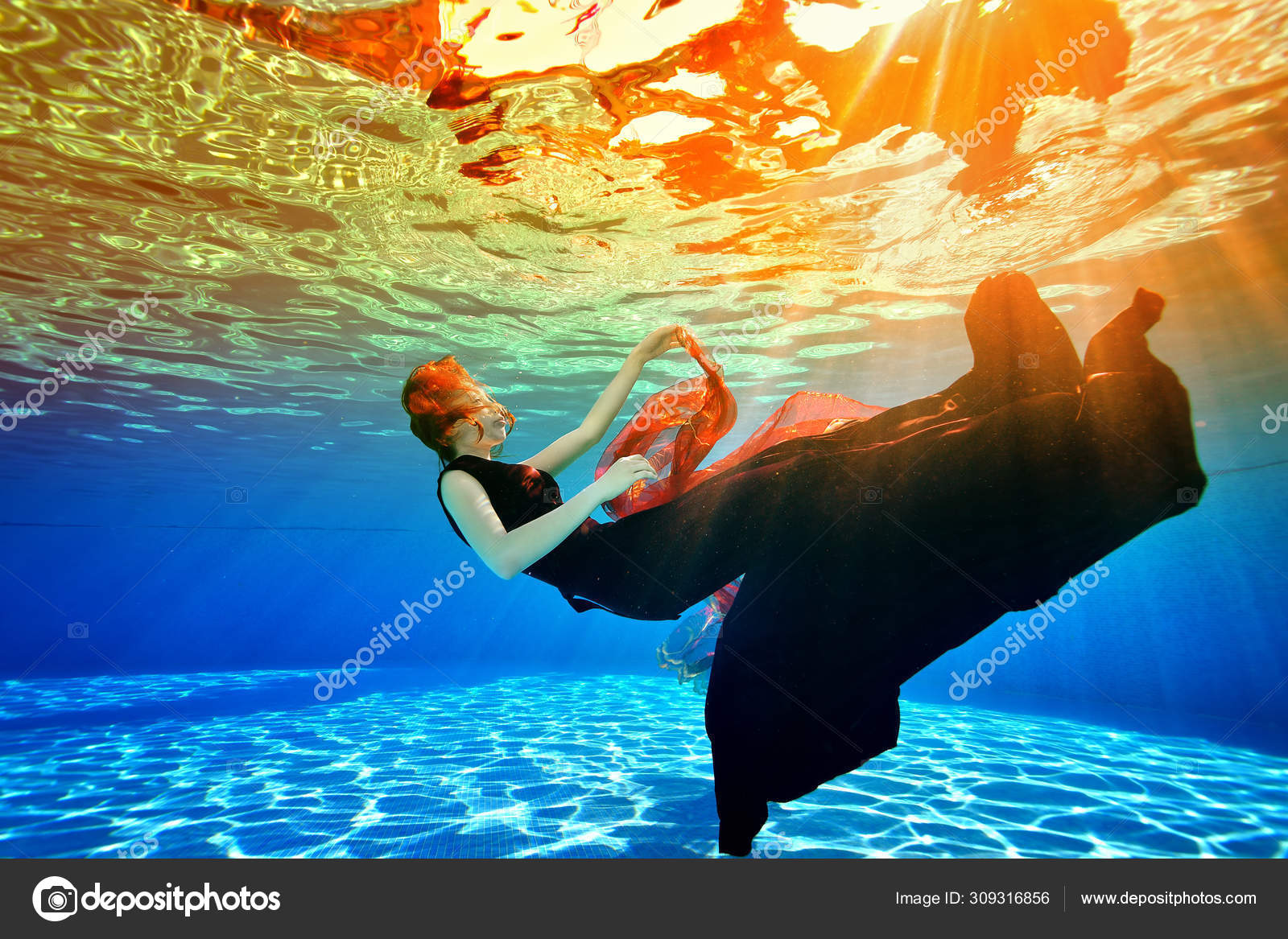 Imagem subaquática surreal. Uma jovem afunda de volta ao fundo da piscina  em um vestido de Borgonha, com cabelo vermelho, contra a luz solar da  superfície. Conceito . — Foto © AlexBard #309316856, image size:1600x1167