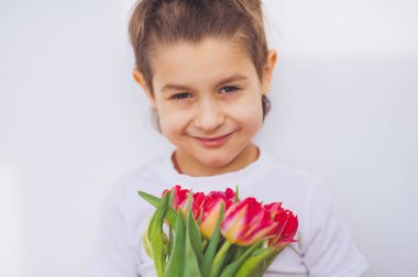 Güneşli ışık kırmızı lale ile gülümseyen şirin bebek çocuk kapalı. 