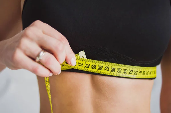 Personal trainer measuring a woman waist  at the fitness gym. Sport and dieting concept.