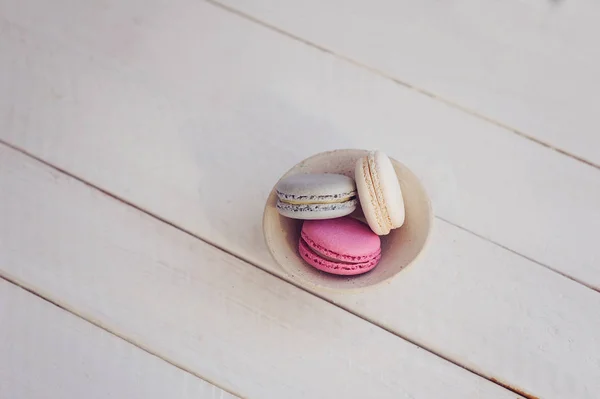Renkli macaroons yukarıdaki üzerinden Beyaz ahşap zemin üzerinde. Metin için yer. 