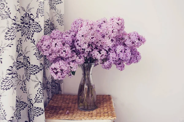 Bouquet of lilacs in a glass vase. Lilac flowers in vintage style against white background.