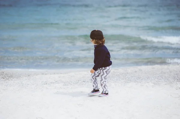 Beach, güzel deniz kumsalda güzel yaz günü yürüyüş şapkalı küçük çocuk eğleniyor