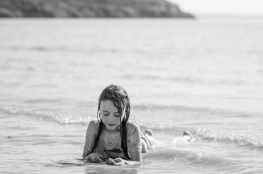 Çocuk sörf siyah beyaz yalan. Denizde oynayan genç kız kayıp kendi düşüncelerinde