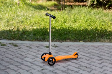 Turuncu bir çocuk scooter yolda duruyor. Summer, dinlenme, spor