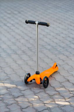 Turuncu bir çocuk scooter yolda duruyor. Summer, dinlenme, spor