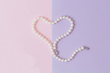 İnci kalp pembe-gri arka plan üzerinde. Düz yatıyordu, en iyi görünümü