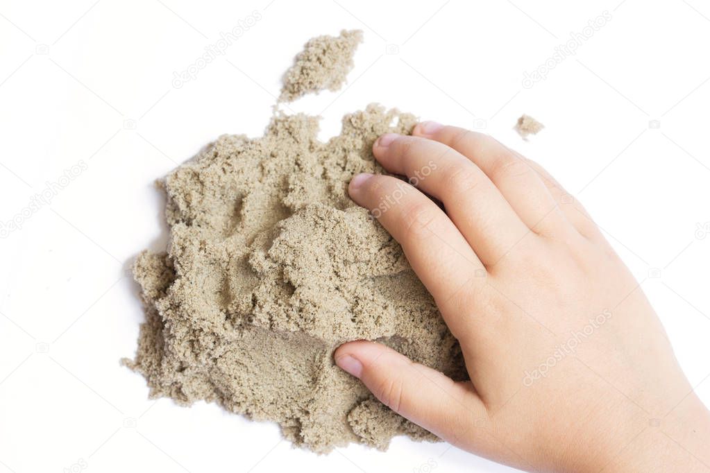 Child playing with kinetic sand. Hand of the child in the sand c