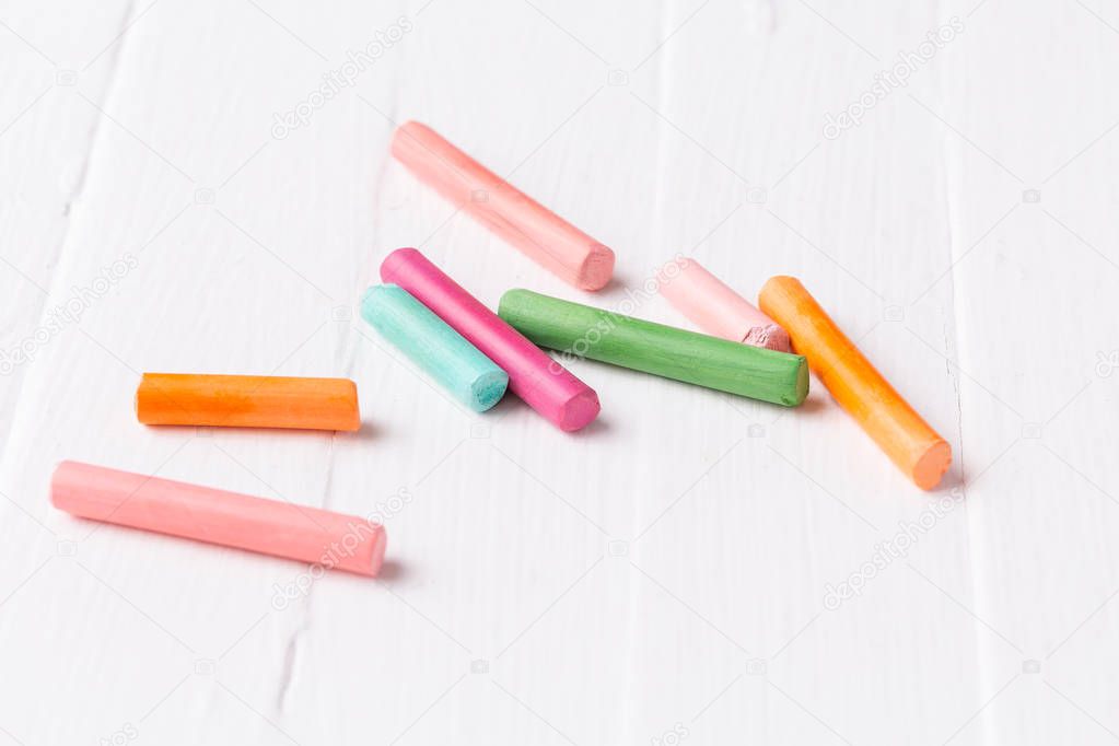 Multicolored crayons, pastel. Green, yellow, pink, purple, blue. Painted Pastels white blackboard