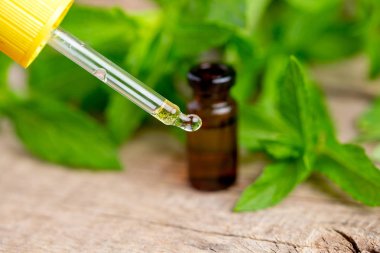 Doğal yeşil arka plan bulanık şişesinde içine damlayan nane yağı