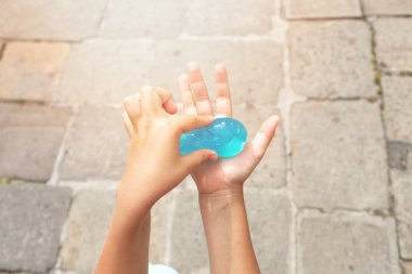 Çocukların elleri yoğurun, şeffaf Turkuaz balçık gösterir. Evin dışında Venedik'in arka planında. Sunray