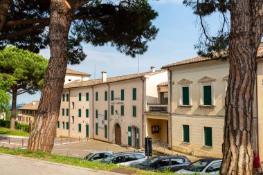 A view of the Museum Gipsoteca Antonio Canova in Italy filled with statues by the great sculptor. Surrounded by tall trees and parked cars, it showcases a peaceful urban environment with natural beauty. 