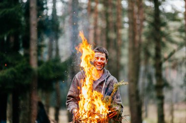 yanan odun elinde tutan genç adam
