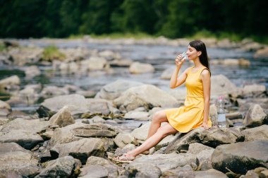 Genç kadın içme suyu kıyısında taşlarla nehir bankada