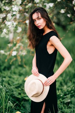 Bahar çiçek açan bahçede poz şapka ile genç esmer kadın