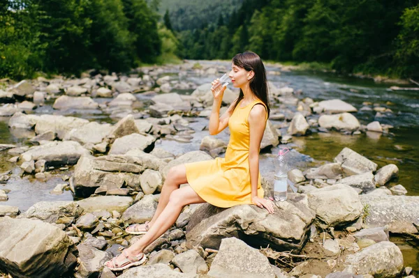 Mujer Joven Bebiendo Agua Orilla Del Río Con Piedras Orilla —  Fotos de Stock