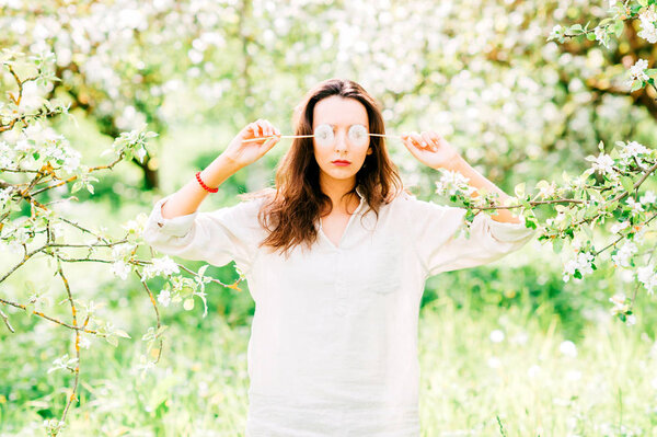 portrait of young woman with dandelions in spring blooming garden