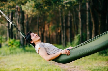 Genç adam hamakta güneşli gün yaz ormandaki rahatlatıcı