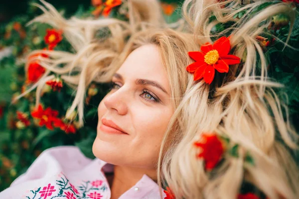 beautiful blond woman in embroidered dress lying in flowers