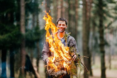 ormanda yanan odun tutan adam