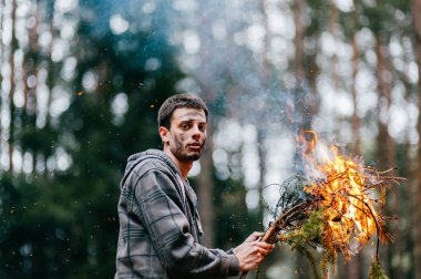 ormanda yanan odun tutan adam